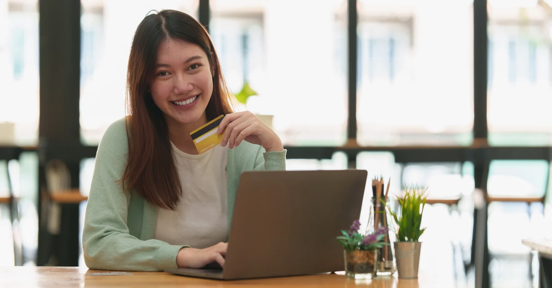 A lady smiling while holding a credit card 